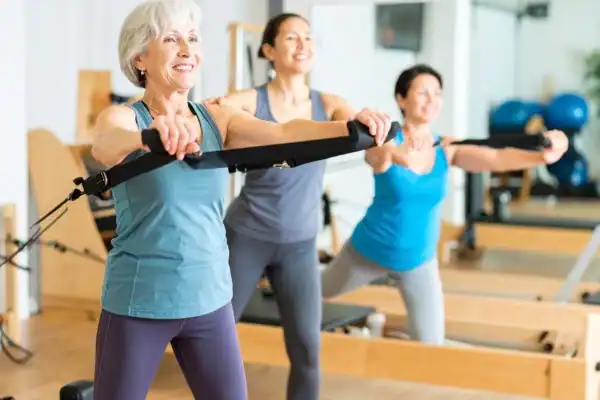 Toning Arms After 60: Empowering Womens Fitness Through Effective Weight Training 2 older woman doing weight training Walton on the Hill and resistance in the gym to tone upper arms