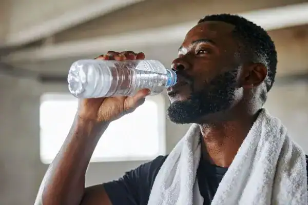 Hydration: The Secret Ingredient for a Toned Stomach and Enhanced Fitness 1 Image of man drinking water to improve hydration Walton on the Hill after work out.